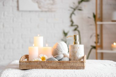 Spa composition with burning candles on couch in salon, closeup