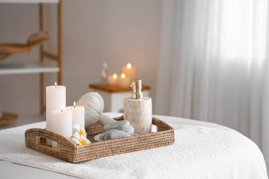 Spa composition with burning candles on couch in salon, closeup