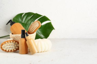 Hafif arka planda kozmetik ürünler, banyo malzemeleri ve palmiye yaprağı.