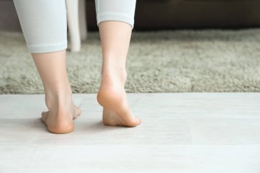 Çıplak ayaklı kadın evde ısıtma sistemi ve arka planı var.