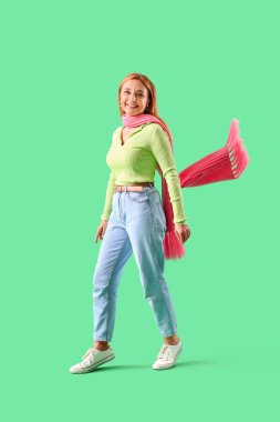 Yeşil arka planda atkısı olan şık, olgun bir kadın.