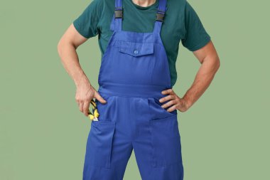 Yeşil arka planda üniformalı erkek tamirci.