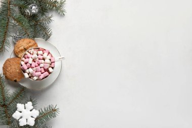Bir fincan lezzetli Noel kakaosu, marşmelov, kurabiye, köknar dalları ve beyaz arka planda kar taneleri.