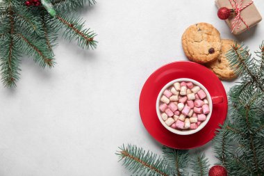 Lezzetli bir fincan noel kakaosu, şekerleme, kurabiye, hediye kutusu ve beyaz arka planda köknar dalları.