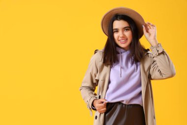 Sarı arka planda şık bir kapüşonlu güzel genç kadın.