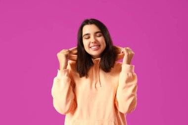 Mor arka planda şık bir kapüşonlu güzel genç kadın.