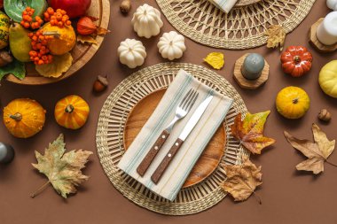 Kahverengi arkaplanda sonbahar dekoru ve mumlarla süslü masa ayarları