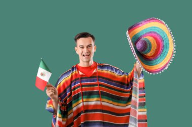 Meksika bayrağı ve yeşil arka planda şapkası olan yakışıklı bir adam.