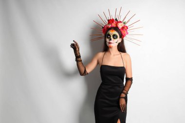 Açık arkaplanda boyalı kafatası olan genç bir kadın. Meksika Ölüler Günü (El Dia de Muertos) kutlamaları