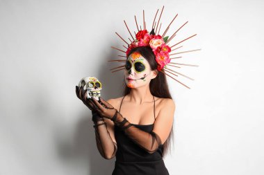 Açık arkaplanda boyalı kafatası olan genç bir kadın. Meksika Ölüler Günü (El Dia de Muertos) kutlamaları