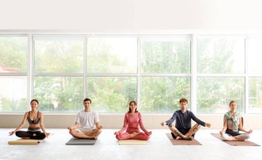 Spor salonunda meditasyon yapan bir grup genç.