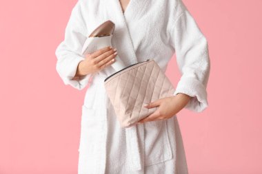 Kozmetik çantalı ve pembe arka planda modern fotoğraf makinesi olan güzel bir kadın.