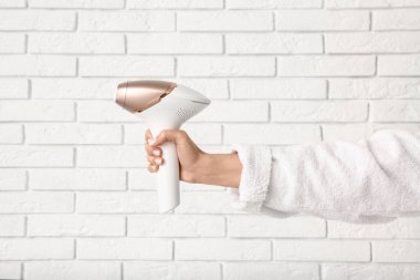 Beyaz tuğlalı arka planda modern fotoğraf makinesi olan bir kadın el.