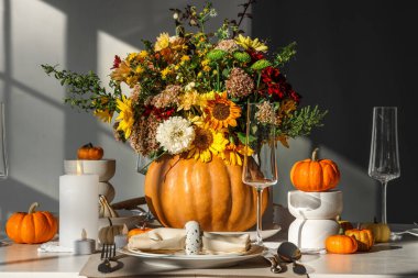 Farklı sonbahar çiçekleri servis edilen yemek masasında balkabağında.