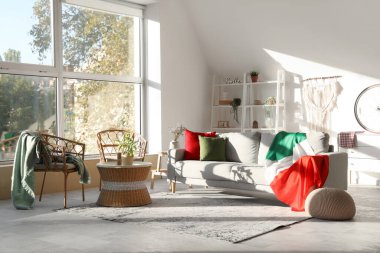 Oturma odasının içinde kanepenin üzerinde İtalyan bayrağı var.