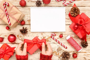 Hediye kutuları, Noel süsleri ve beyaz ahşap arka planda boş kağıt takvimi olan bir kadın.