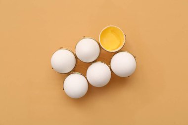 Çatlak tutucu ve bej arka planda tavuk yumurtası.