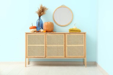 Kabaklı ahşap dolap, otlar ve mavi duvarın yanındaki ayna.