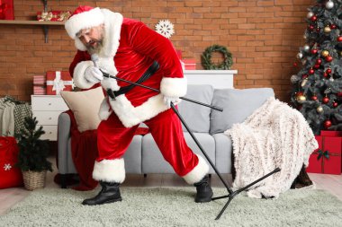 Noel Baba ve mikrofon Noel için dekore edilmiş oturma odasında şarkı söylüyor.