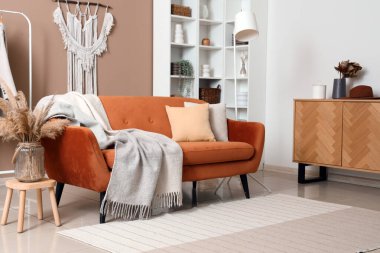 Kahverengi kanepesi, sıcak battaniyesi ve otları olan modern oturma odasının içinde.