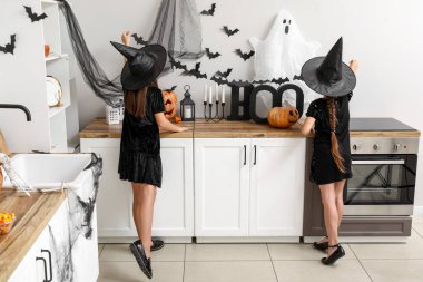 Cadılar Bayramı için süslenmiş balkabaklarıyla cadı gibi giyinmiş şirin küçük kızlar.