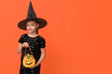 Cadılar Bayramı 'nda turuncu çantalı cadı gibi giyinmiş şirin küçük kız.