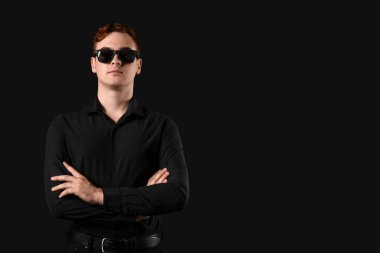 Siyah arka planda güneş gözlüklü genç bir adam. Kara Cuma indirimi