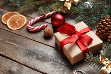 Noel süsleri ve kahverengi ahşap arka planda hediye kutusu olan güzel köknar dalları.