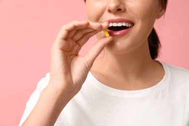 Pembe arka planda hap alan kadın, yakın plan.