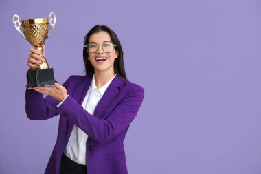 Leylak arka planında altın kupası olan genç bir iş kadını.