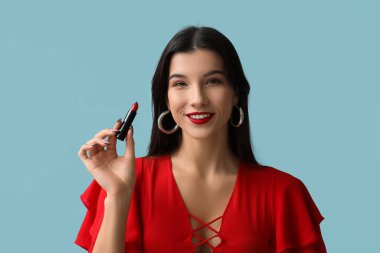 Mavi arka planda kırmızı ruju olan güzel bir genç kadın.