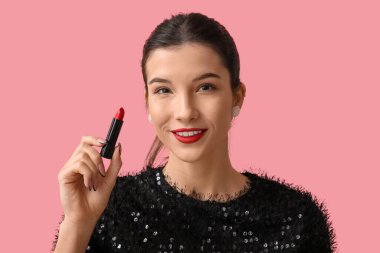 Pembe arka planda kırmızı ruju olan güzel bir genç kadın.