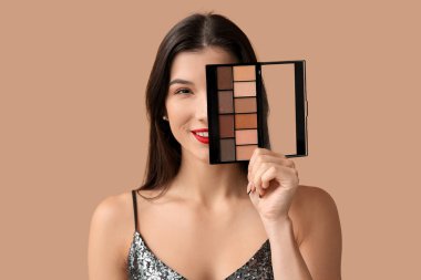 Kahverengi arka planda göz falı paleti olan güzel genç bir kadın.