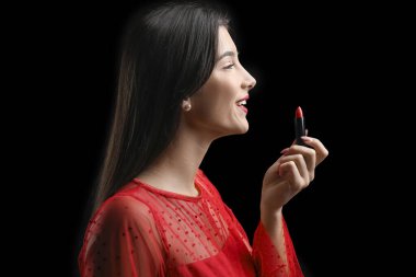 Siyah arka planda kırmızı ruju olan güzel bir genç kadın.