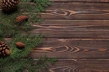 Koyu ahşap arka planda köknar konileri olan Noel dalları