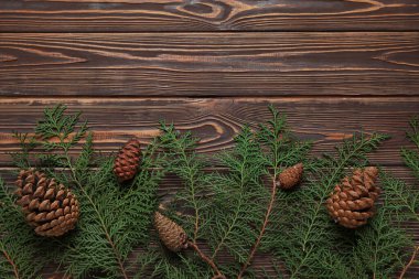 Koyu ahşap arka planda köknar konileri olan Noel dalları