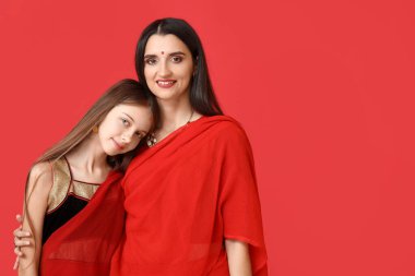 Güzel bir anne ve kızı kırmızı arka planda sari giyiyor. Divaly kutlaması