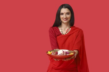 Kırmızı arka planda mumları ve çiçekleri olan sarili güzel bir Hintli kadın. Divaly kutlaması