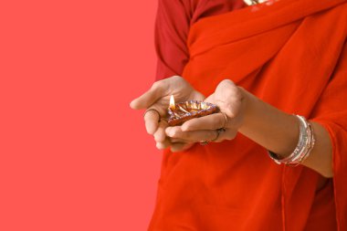 Kırmızı arka planda diya lambası olan sarili güzel bir Hintli kadın. Divaly kutlaması