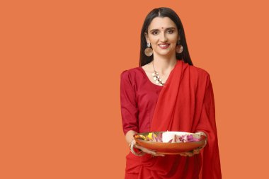 Sari giymiş, turuncu arka planda çiçekleri olan güzel bir Hintli kadın. Divaly kutlaması