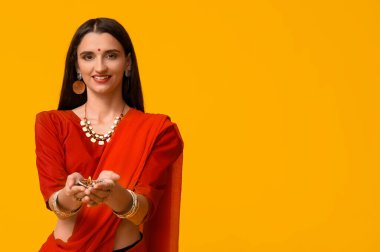 Sarı arka planda diya lambası olan sarili güzel bir Hintli kadın. Divaly kutlaması