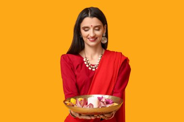 Sarı arka planda mumları ve çiçekleri olan sarili güzel bir Hintli kadın. Divaly kutlaması