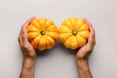 Hafif arka planda balkabakları olan erkek eller.