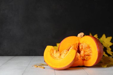 Tohumlarla taze balkabağı kes ve beyaz fayans masasında sonbahar yaprakları