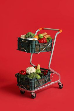 Kırmızı arka planda yiyecek dolu alışveriş arabası.