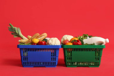 Kırmızı arka planda yiyecek dolu alışveriş sepetleri.