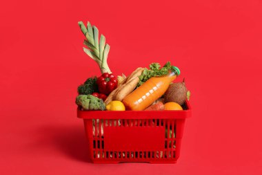 Kırmızı arka planda yiyecek dolu alışveriş sepeti