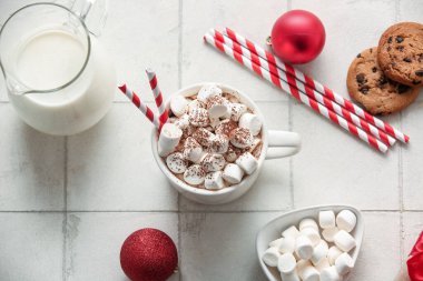 Bir fincan kremalı sıcak kakao, Noel topları ve beyaz fayanslı tatlı kurabiyeler.