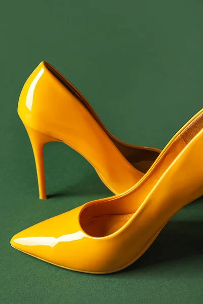 Stylish yellow high heels on green background