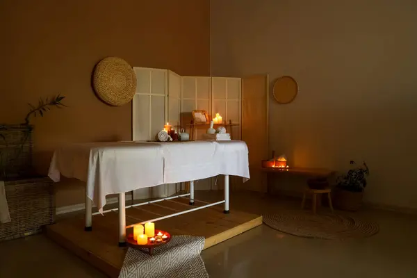 Interior of dark spa salon with couch and burning candles
